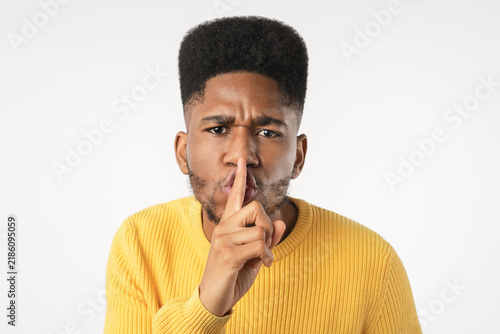 Quadro su tela Close up of dark skinned man making silence gesture isolated over white backgrou