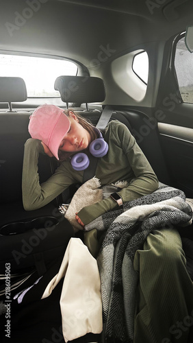 Tired preteen girl sleeping in back seat of car during family road trip.