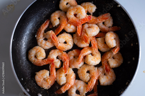 Фотография Pink prawns sizzle inside a round black frying pan from an overhead view in Corfu,Greece