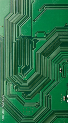 Macro shot of a green printed circuit board showing intricate copper traces and electronic hardware components