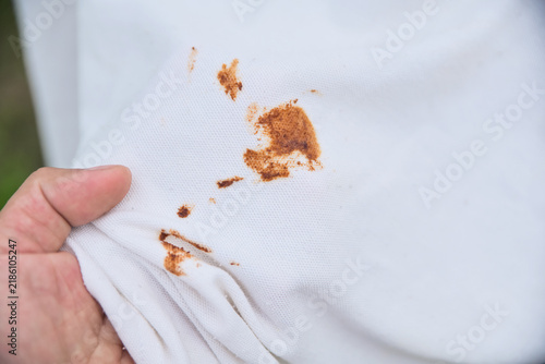 Brown sauce or rust spots scattered on white polo shirt fabric. Concept of dirty clothes