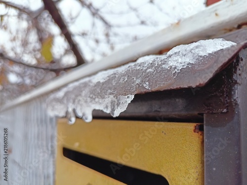 Close-up of an ice-covered metal mailbox lid in winter