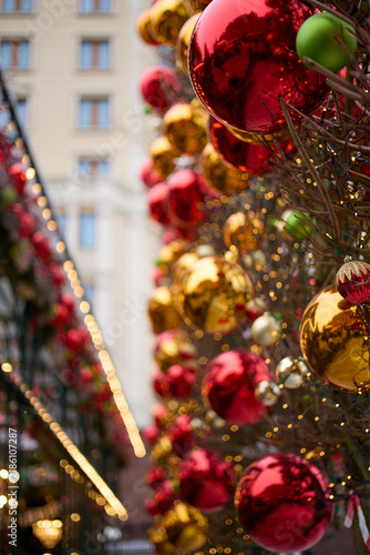 Cinematic festive street scene featuring elegant Christmas trees covered with glossy red, gold, and green baubles and warm decorative lights. Shallow depth of field creates beautiful golden bokeh