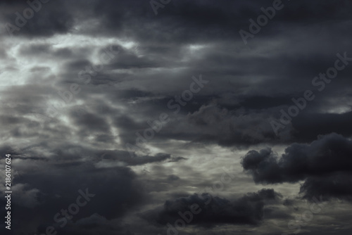 The image shows a vast sky completely dominated by dense storm clouds. Multiple layers of dark gray, charcoal, and silver gray clouds overlap across the entire frame, creating strong atmospheric depth