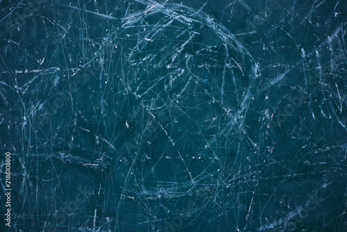 scratched teal-blue surface, featuring dense chaotic white scrape marks and subtle color flecks that create a raw, distressed texture. 