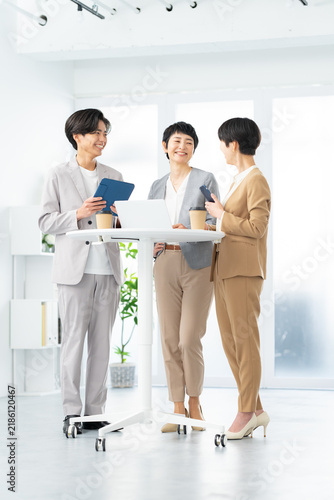 Bild auf Leinwand 明るいオフィスで立ち会議をする笑顔のビジネスパーソン3人