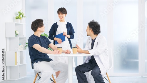 Fototapeta 休憩室でコーヒーを片手に談笑する医師と医療スタッフ3人