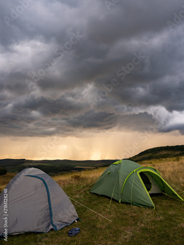 Camping Tents Under Dramatic Storm Clouds in Open Wilderness Landscape