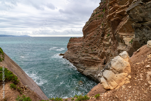 Canvas Print Dramatic layered rock formations plunge into the churning turquoise waters of th