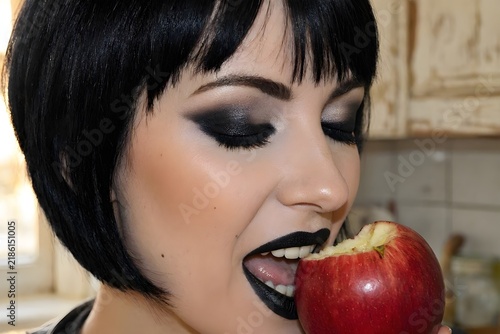 Plakat w ramie donna con occhi chiusi che mangia una mela con make-up scuro 