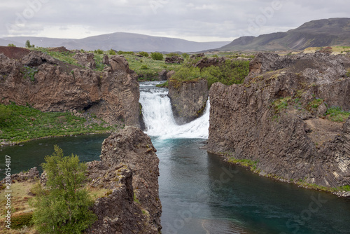 Bild auf Leinwand Hjalparfoss waterfall in a broad volcanic mountain landscape within Iceland