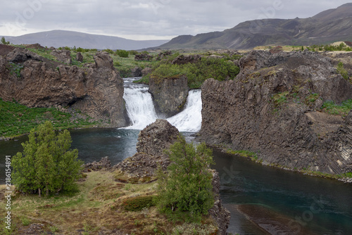 Konstfotografi Hjalparfoss waterfall beyond a green volcanic terrain at an impressive natural landmark in Iceland