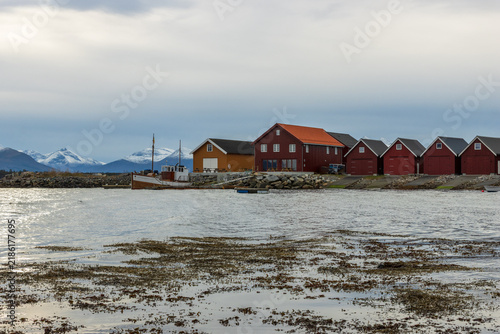 Scenic harbor in Molde, Norway with traditional wooden huts and snow-capped peaks of Tresfjord