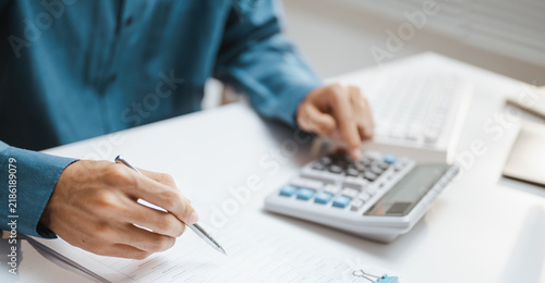 He writes carefully beside a device as payroll review guides calculation for human work and human resources, while payroll notes support review through calculation of human tasks and human resources.