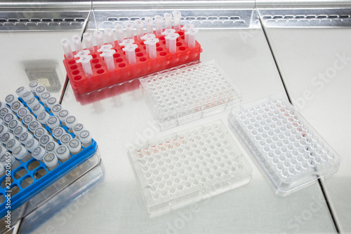 Foto Immunological plates for antibody reactions lie on the laboratory bench next to boxes of test tubes