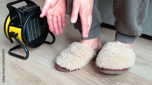 An electric heat gun for heating a house indoors a person is warming up in a freezing cold house.