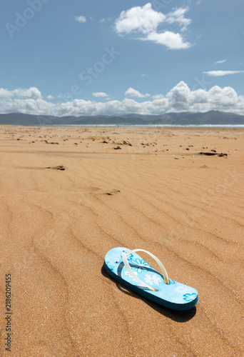Lost blue flip-flop on vast sandy beach
