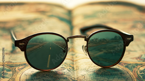 Vintage sunglasses resting on an old travel map reflecting a road ahead