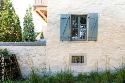 Картината върху платно View of historic stone plastered wall with open pale blue shutters on window ove