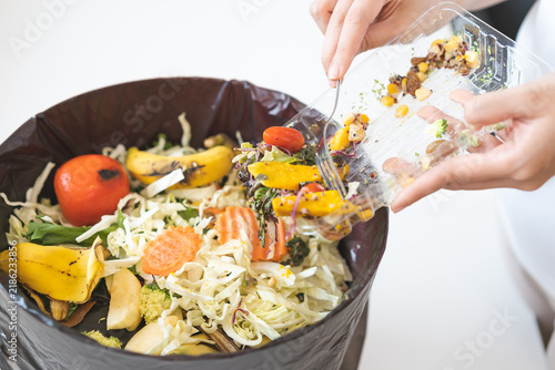 Картината върху платно Compost from leftover food asian young housekeeper woman, female hand holding salad box use fork scraping waste, rotten vegetable throwing away into garbage, trash or bin