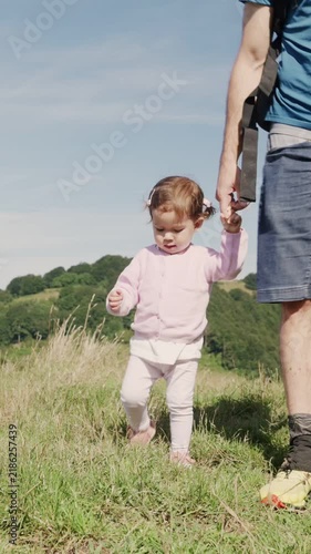 Little girl walking hand in hand with her dad on a mountain trail