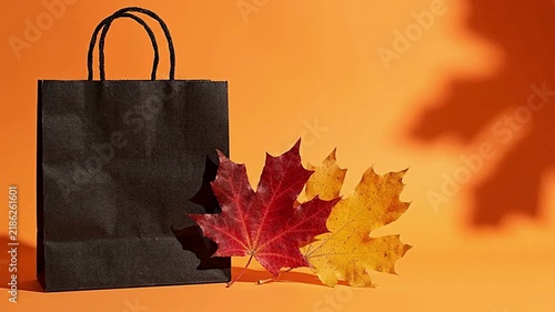 Black shopping bag next to colorful maple leaves in this seasonal fall motion animation video clip
