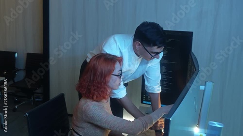 Programmers working at night analyzing code on monitors in a modern office. Software developers collaborating on debugging cybersecurity and data programming projects. Ai coding Software technician.