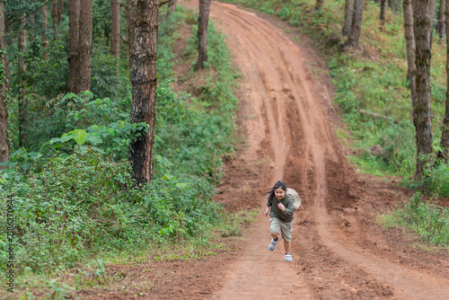 Foto A young girl races along a dirt road through the pine forest