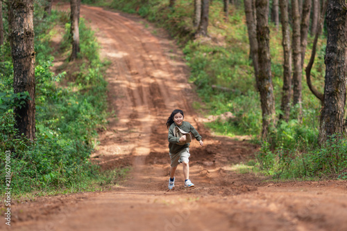 Foto A young girl runs down a forest trail holding her sun hat