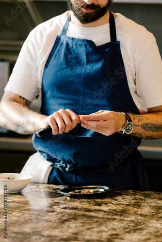 Chef peeling almonds with a specialized tool in a gourmet kitchen
