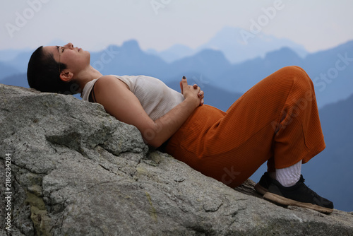 woman resting on a rock during a hike with mountain background