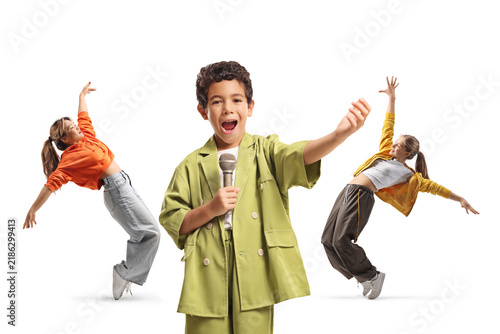 Foto Boy singing into a microphone with two girls dancing behind him