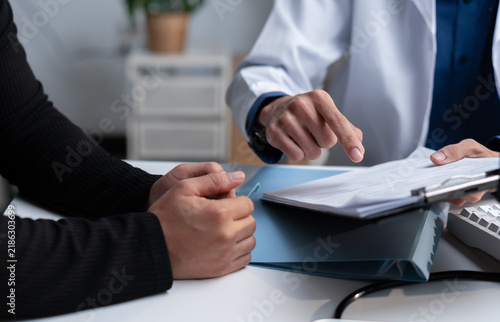 Doctor reviewing medical records with a patient during consultation, explaining healthcare documents, diagnosis, treatment options, clinical results, insurance and personalized care planning.
