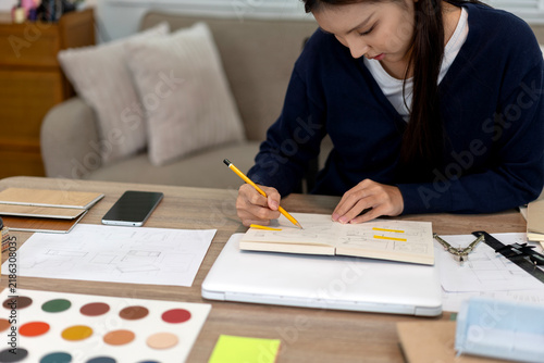 Female Interior Designer Sketching Furniture Layout Ideas with Color Palette at Home Office Desk
