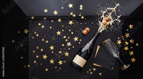 Popping Champagne Bottle with Gold Star Confetti Splash on Black Background