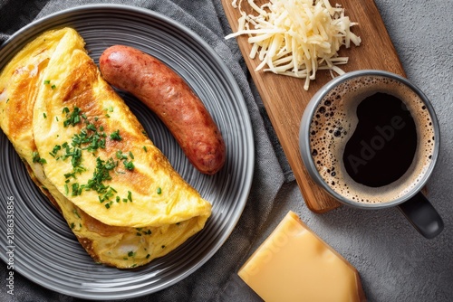 Breakfast plate with omelette, sausage, cheese, and coffee on a table