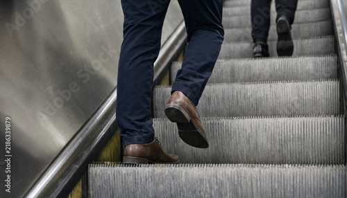 Business people walking up an escalator in a modern office building lobby with moving stairs walking up urban life public space building interior modern architecture formal wear way
