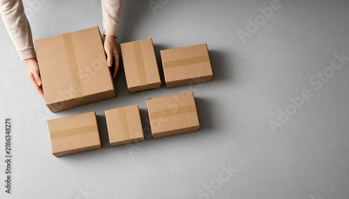 Person hands preparing various brown cardboard delivery packages on a table with cardboard box shipping package parcel delivery package preparation shipping supply small business