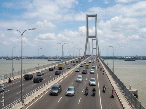 Busy Suspension Bridge with Heavy Traffic and City Skyline Background