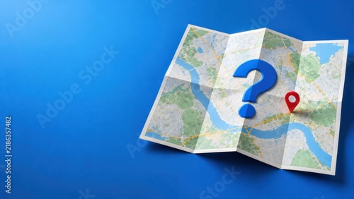 Blue question mark and red location pin placed on folded paper city map over blue background.