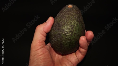 Close-up of a hand holding a fresh green avocado. Perfect for healthy eating, organic food, nutrition, culinary, and natural lifestyle concepts