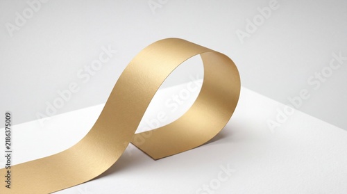 A roll of golden tape on a white surface with a plain background