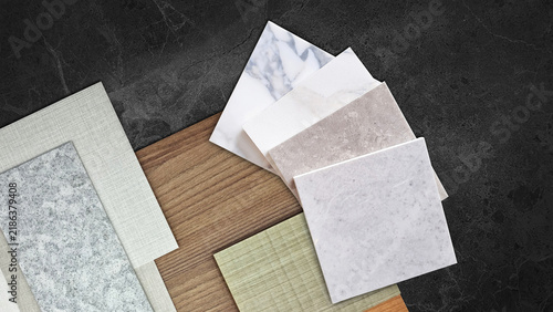 Modern interior design material samples flat lay moodboard featuring marble stone swatches, wood panel, fabric textures on dark granite background surface for architectural planning concept.
