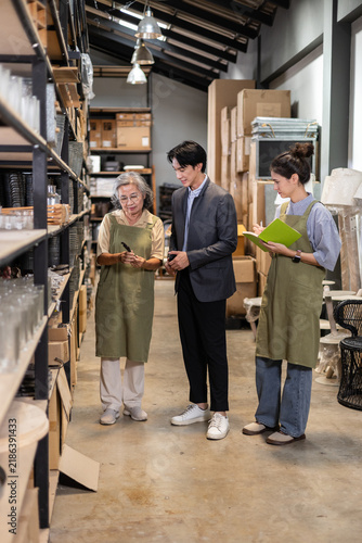 Male Asian investor inspecting family running ceramic warehouse, business discussion with two female shop owner, purchasing and wholesale partnership opportunities