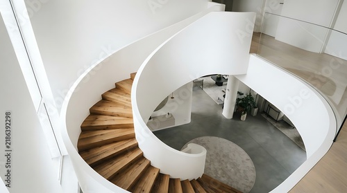 A beautifully designed elegant white spiral staircase with warm wooden steps gracefully descends into a softly illuminated interior architectural detail