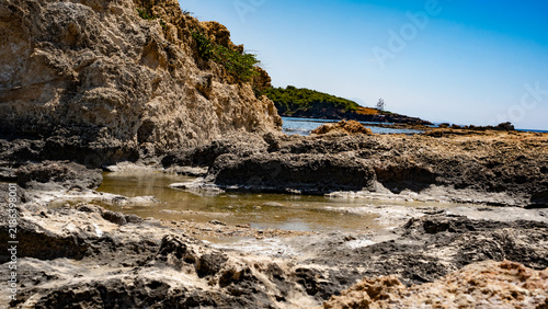 Stunning rocky coastline with clear blue skies and tranquil waters, capturing nature's beauty and serenity.