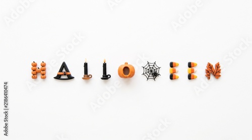Halloween word spelled out with festive holiday objects and miniature decorations on white background