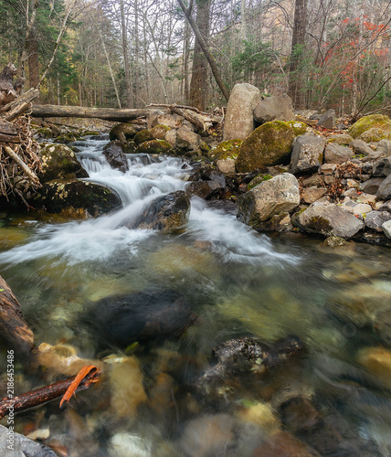 Foto Smolny Creek flowing between large rocks and fallen trees in an autumn forest in Primorsky Krai, Russian Far East
