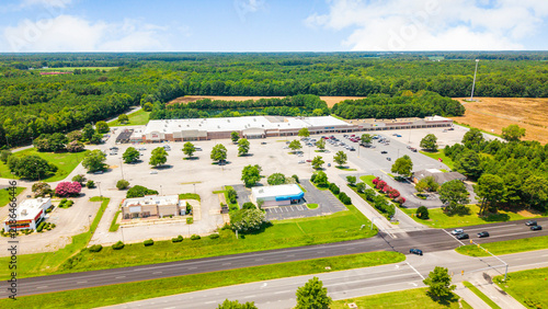 Canvas Print Aerial perspective of a large suburban retail strip mall and adjacent green fiel