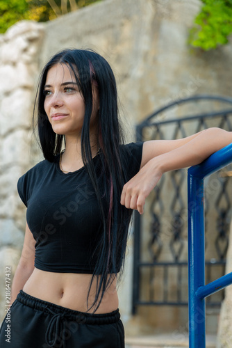 Young woman leaning on blue railing outdoors with a thoughtful s